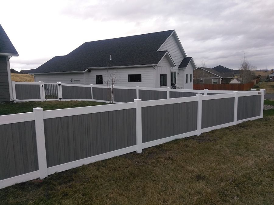 A gray and white fence is in front of a house.