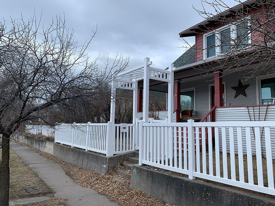 A white fence surrounds a porch of a house.
