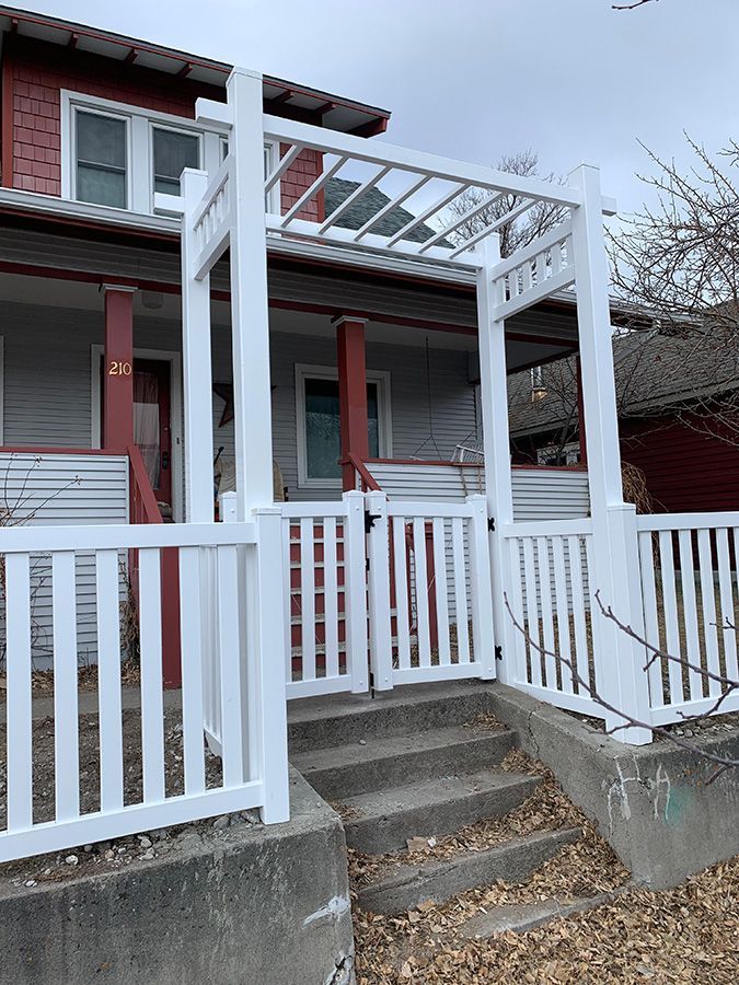 A white fence is surrounding a porch of a house.