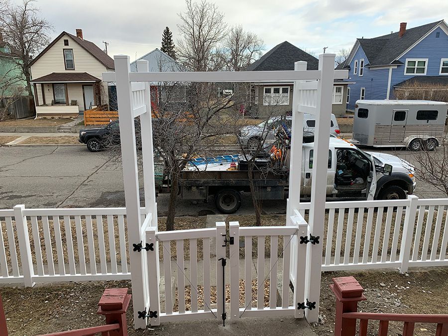A white fence with a gate and a truck in the background.