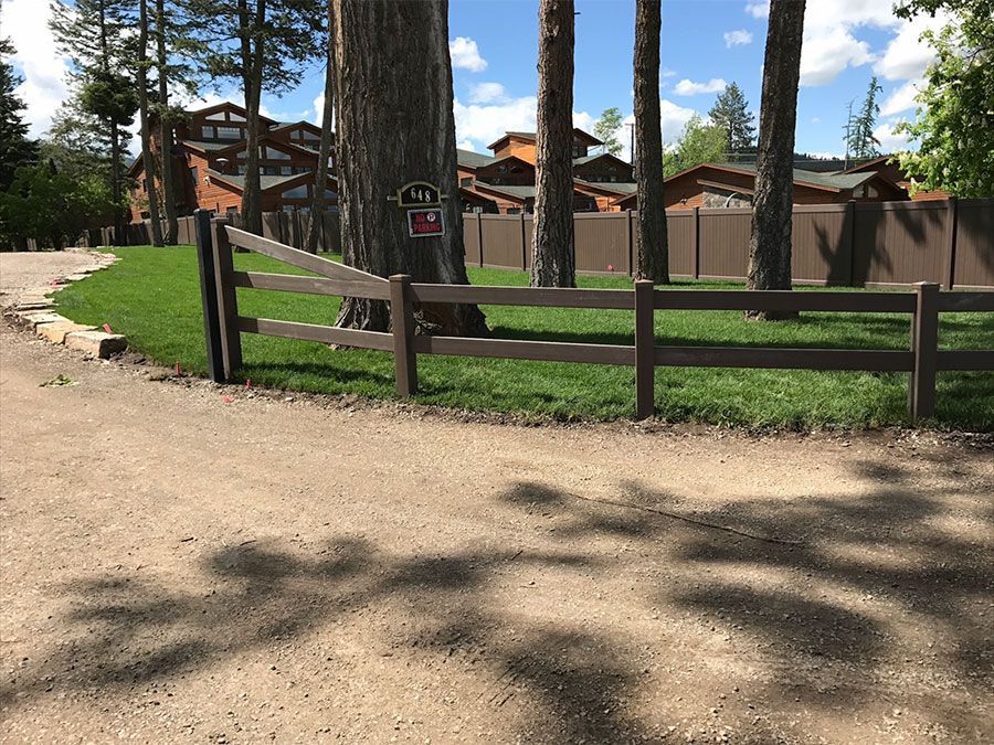 A wooden fence surrounds a grassy area with trees in the background