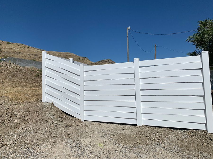 A white fence is sitting on top of a dirt hill.