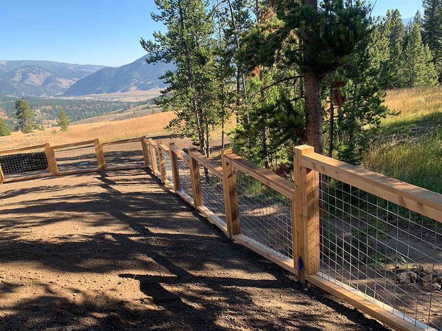 A wooden fence surrounds a dirt path on top of a hill.