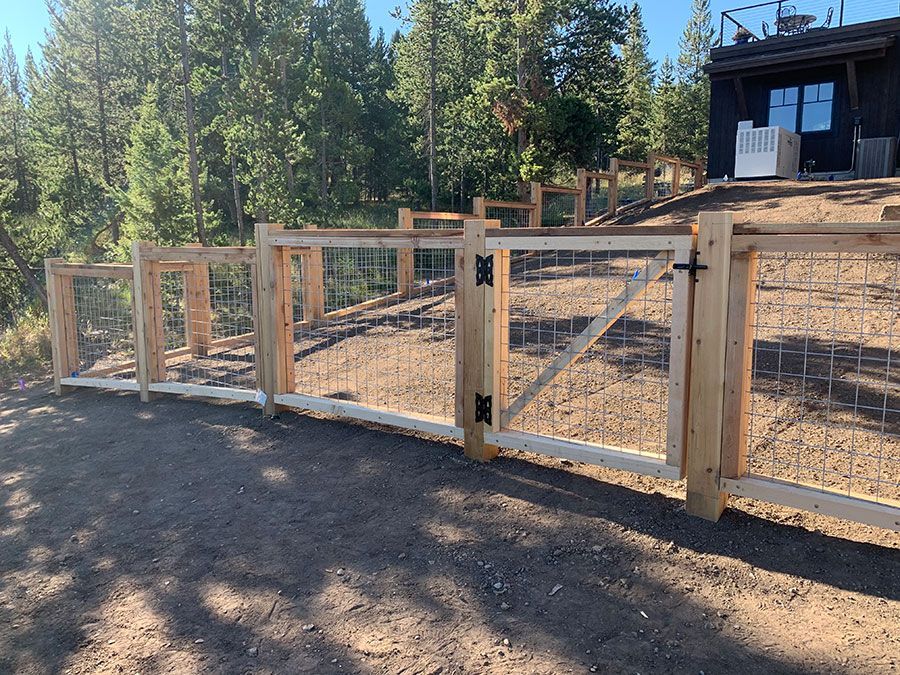 A wooden fence with a gate in front of a house.