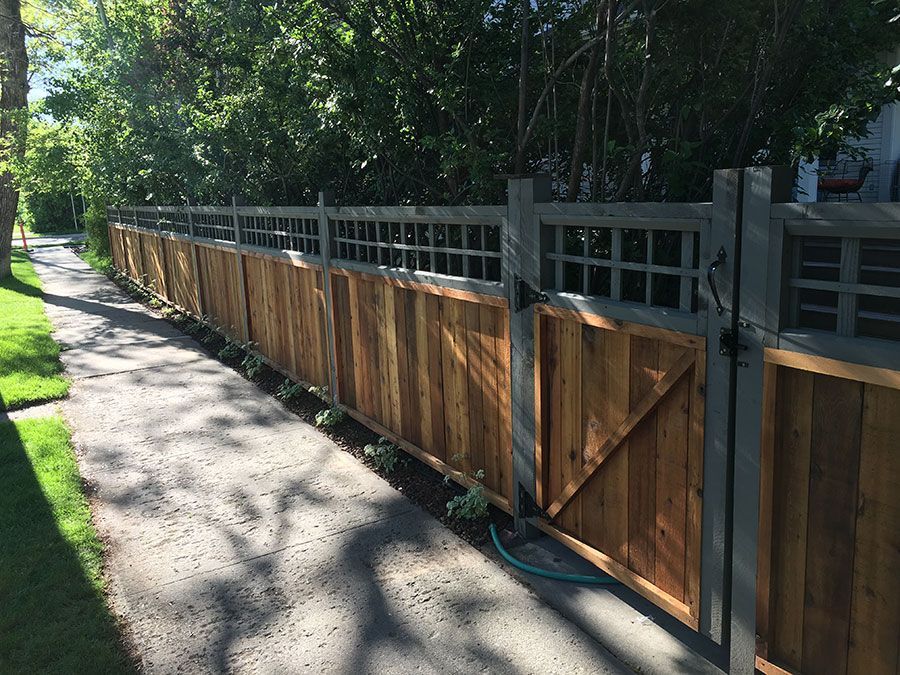 A wooden fence with a gate on the side of a road.