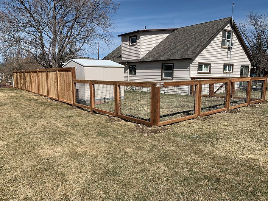 A wooden fence is in the backyard of a house.