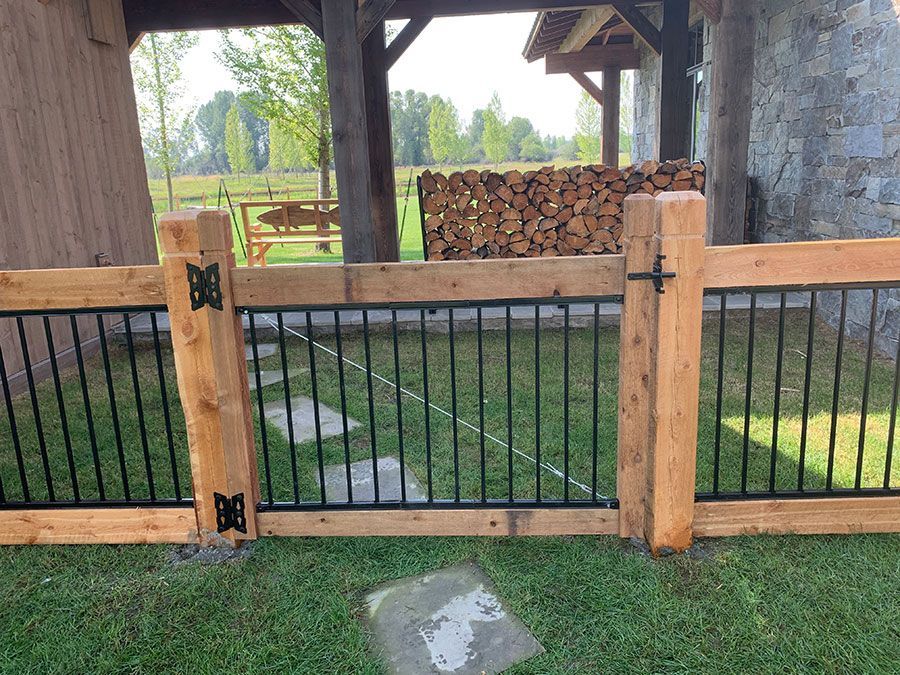 A wooden fence with a metal railing is surrounded by grass.