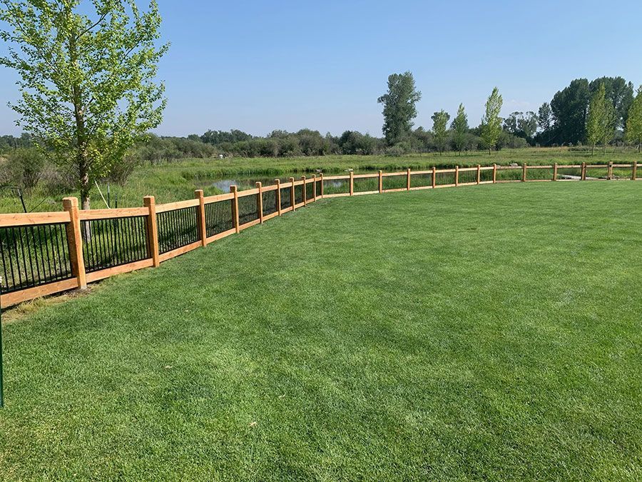 A wooden fence surrounds a lush green field.