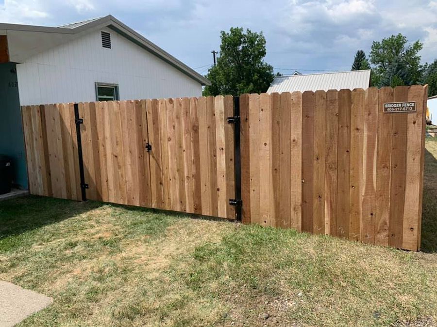 A wooden fence is sitting in the grass in front of a house.