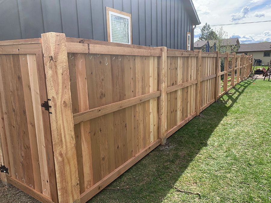 A wooden fence with a gate in the backyard of a house.