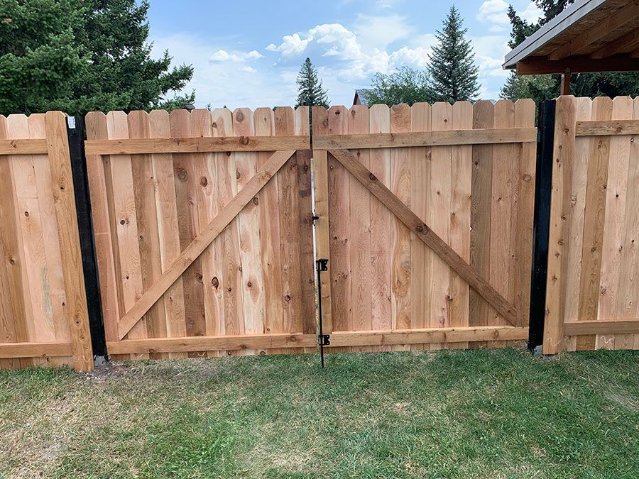 A wooden fence with a gate is sitting on top of a lush green lawn.