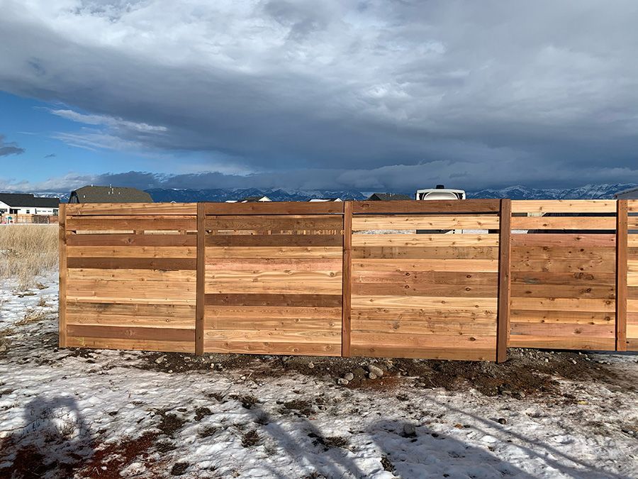 A wooden fence is sitting in the middle of a snowy field.