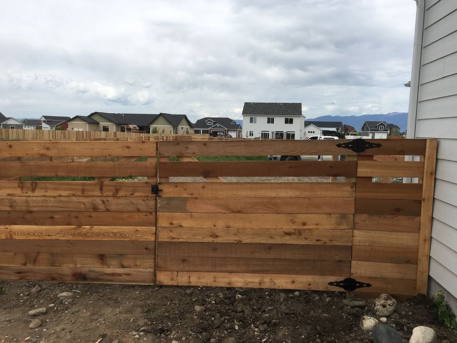 A wooden fence with a gate in front of a house.