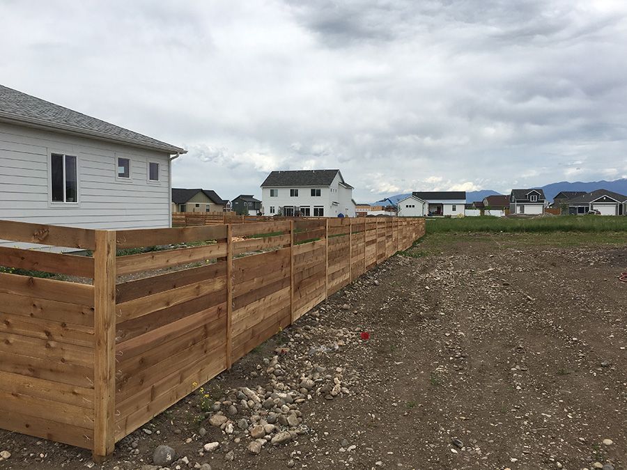 A wooden fence is surrounding a house in a residential area.