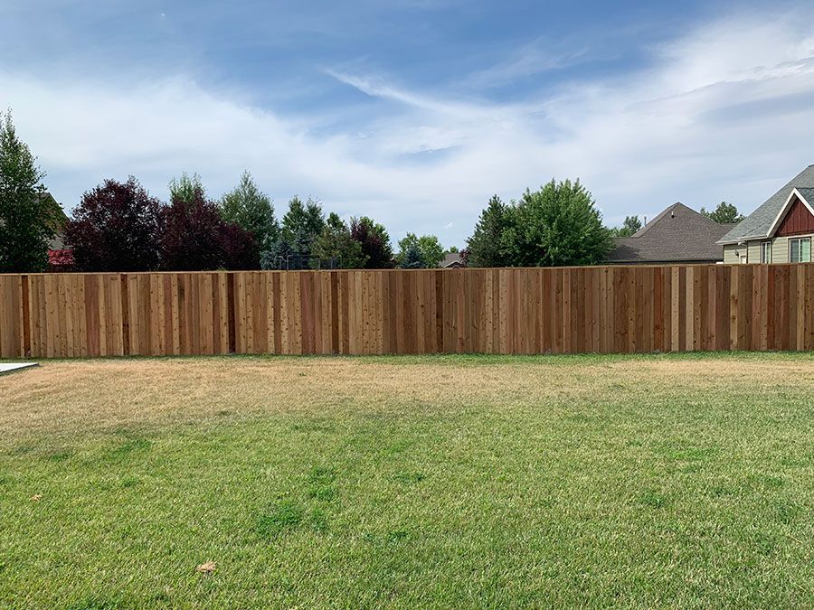 A wooden fence is in the middle of a lush green field.
