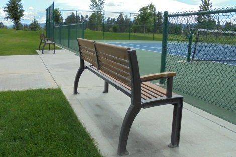 A bench sits in front of a tennis court