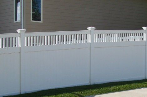 A white fence is sitting in front of a house.
