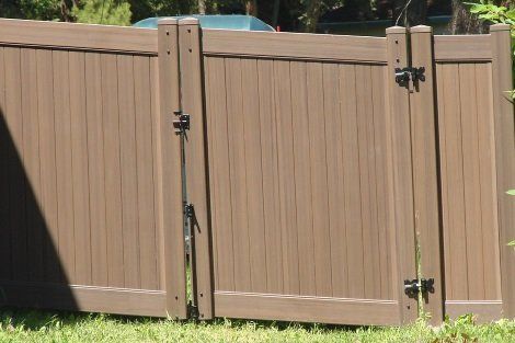 A brown wooden fence with a gate in the grass