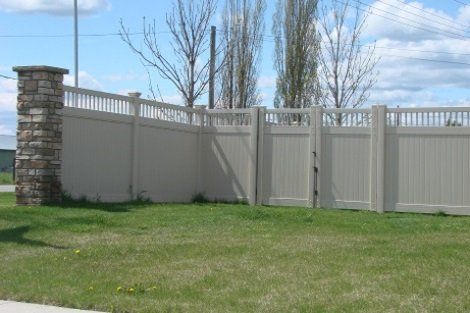 A white fence with a stone pillar in the background
