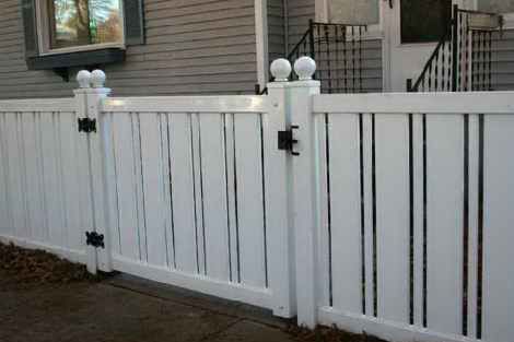 A white fence with a gate in front of a house.