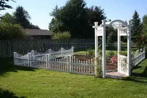 A white picket fence with a gazebo in the backyard.
