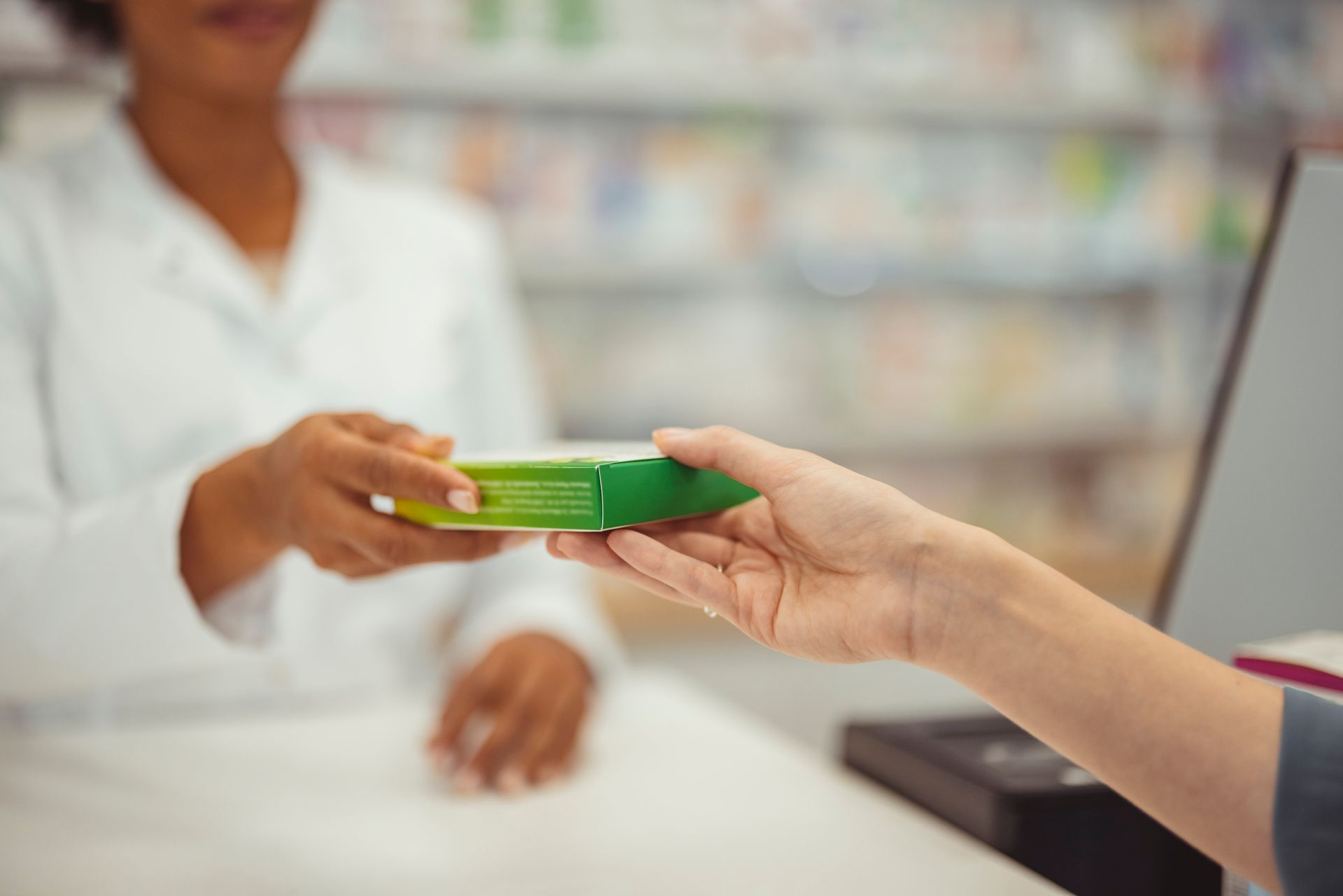 Una persona sta consegnando una scatola di pillole a un farmacista in una farmacia.
