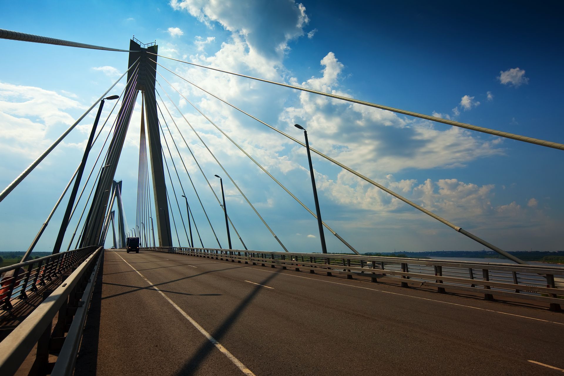 Suspension bridge roadway under a blue sky with cables stretching to a tall tower