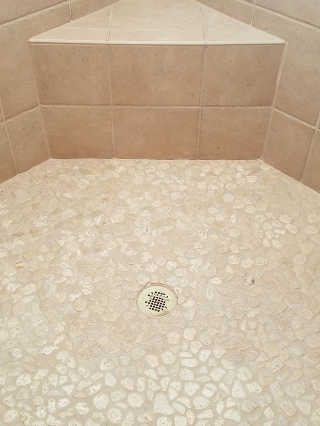A bathroom with a walk in shower with a floral pattern on the wall.