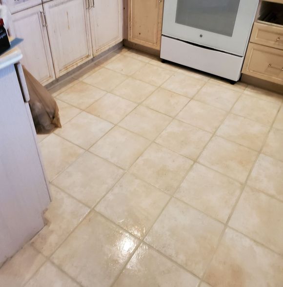 A kitchen floor with white cabinets and a refrigerator.