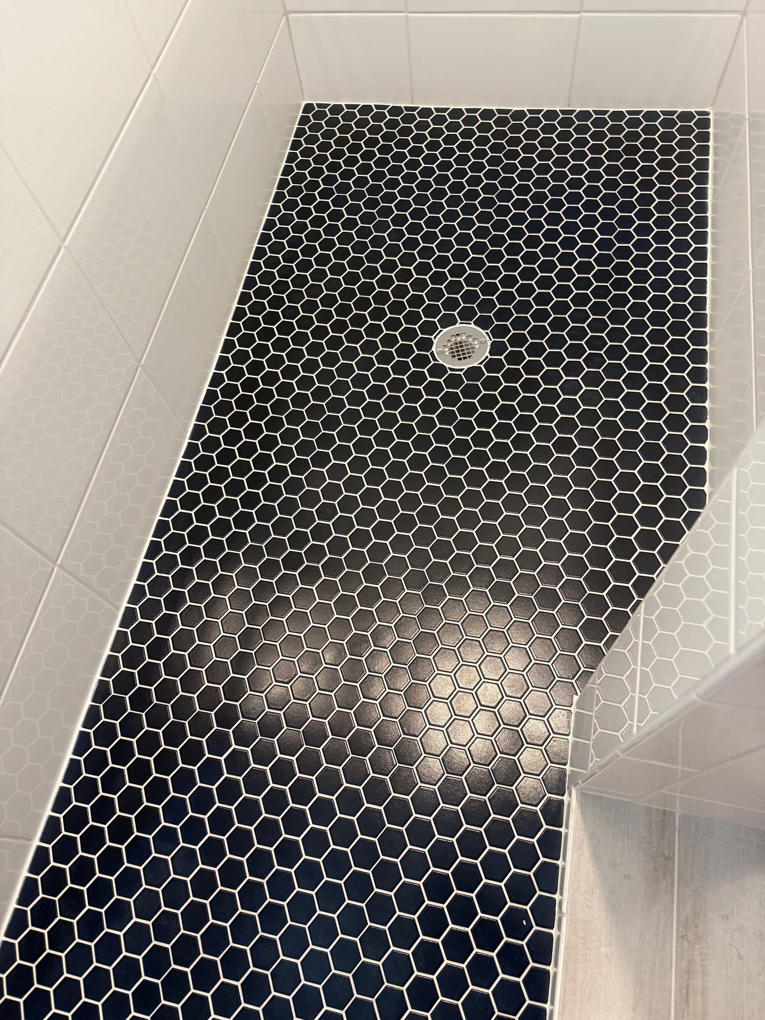 A black and white tiled floor in a bathroom with a drain.