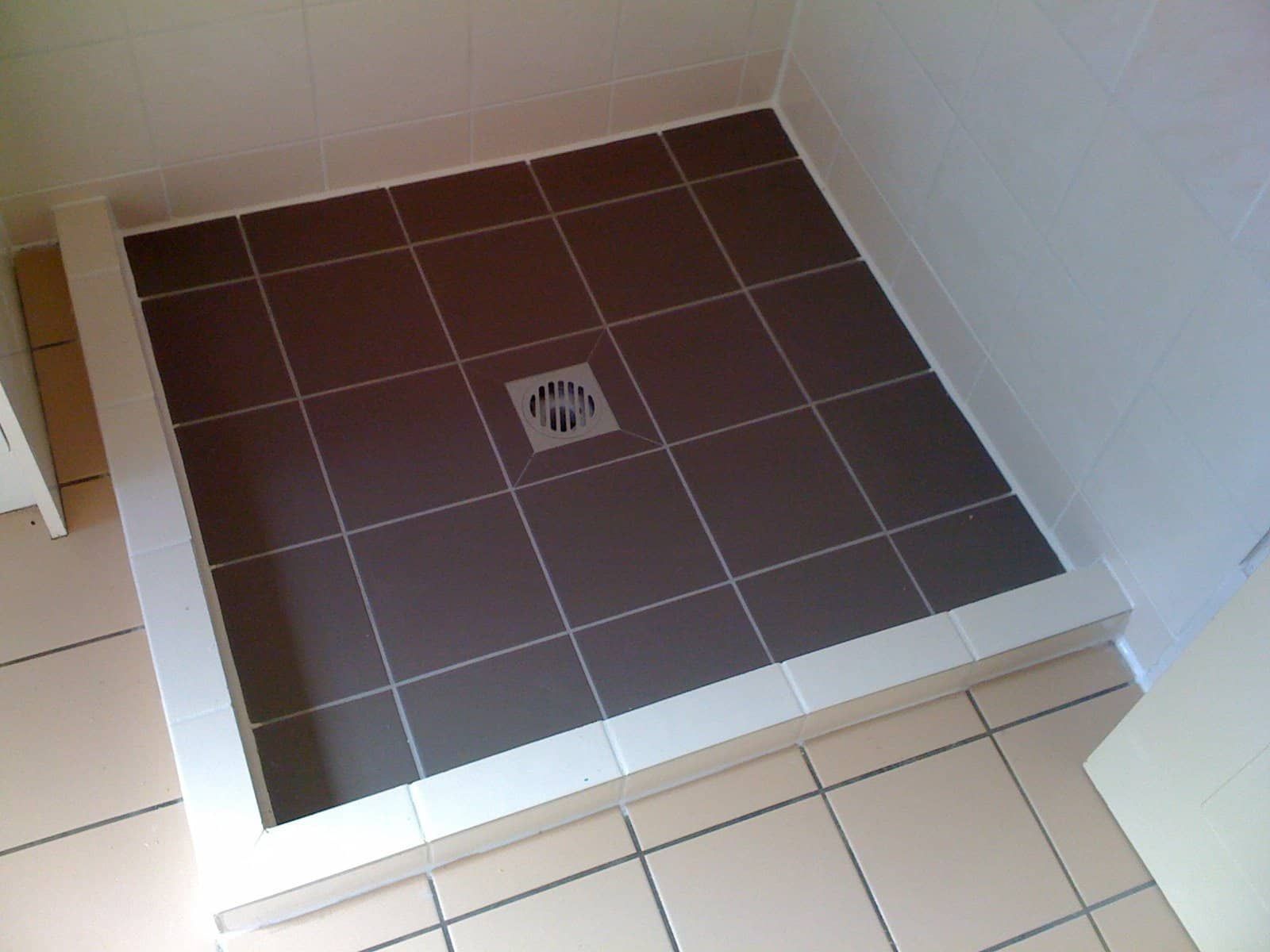 A man is fixing a shower head in a bathroom.