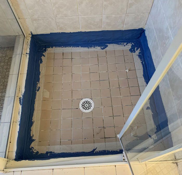 A person is fixing a shower head in a bathroom.