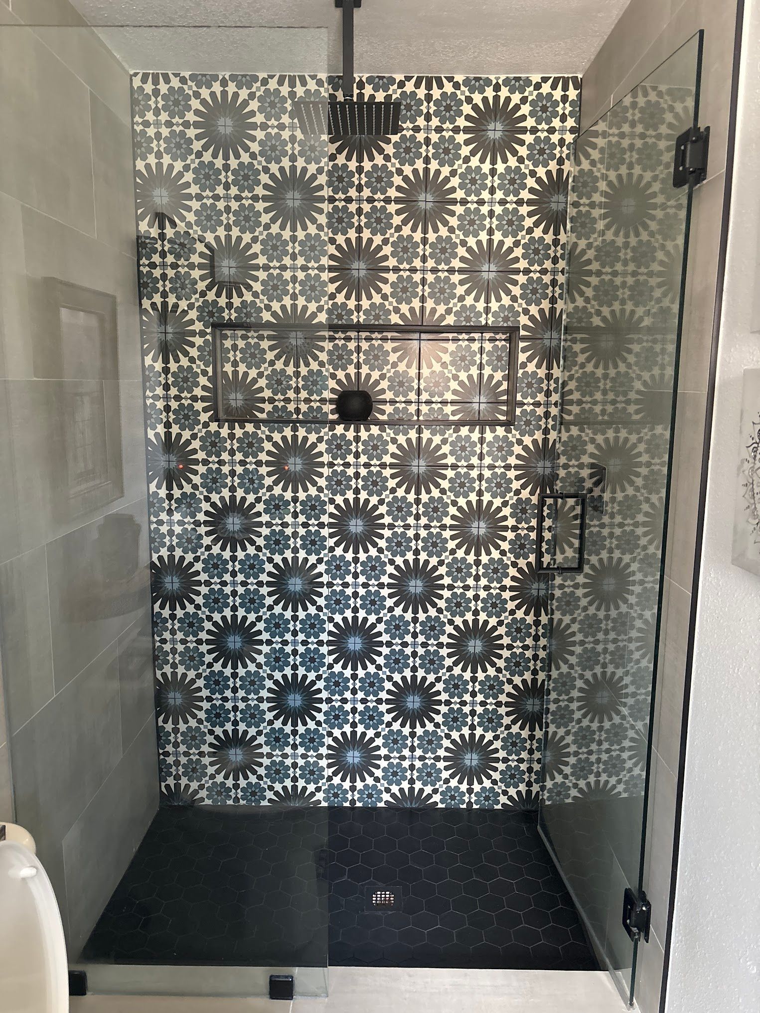 A bathroom with a walk in shower with a floral pattern on the wall.