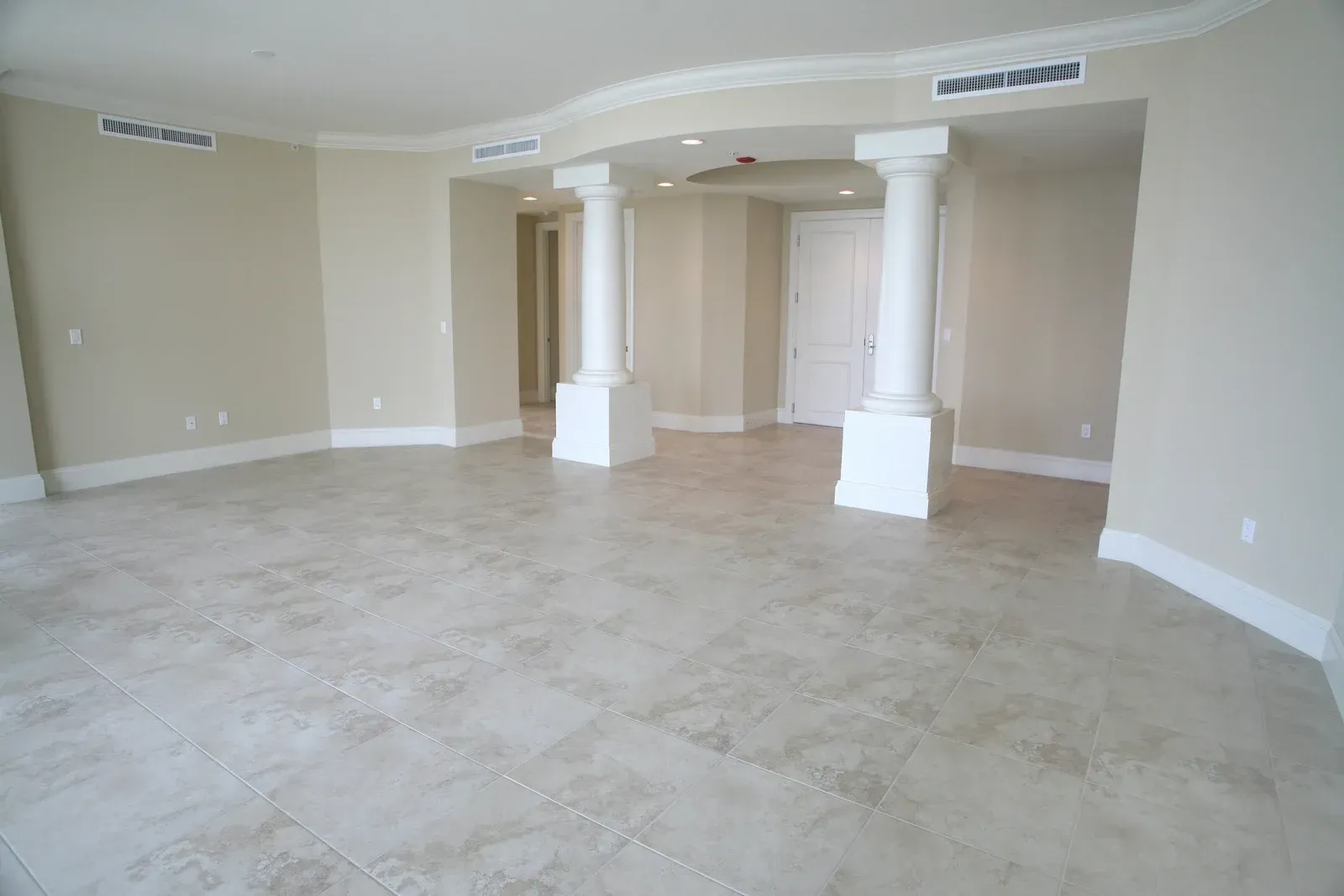 An empty living room with tile floors and white columns
