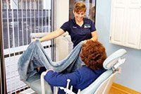 A dental assistant placing a blanket on a patient