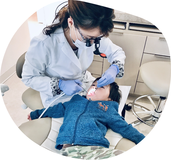Dr. Pham conducting a teeth cleaning on a child.