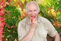 An older man eating an apple