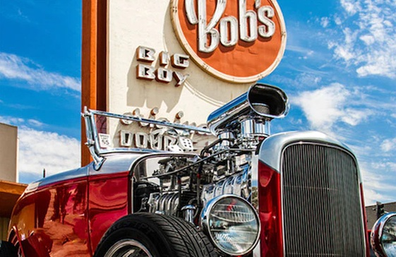 Red hot rod car in front of Bob's Big Boy restaurant sign. Chrome engine.