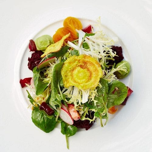 Salad on white plate with spinach, beets, orange segments, and a yellow fried vegetable garnish.