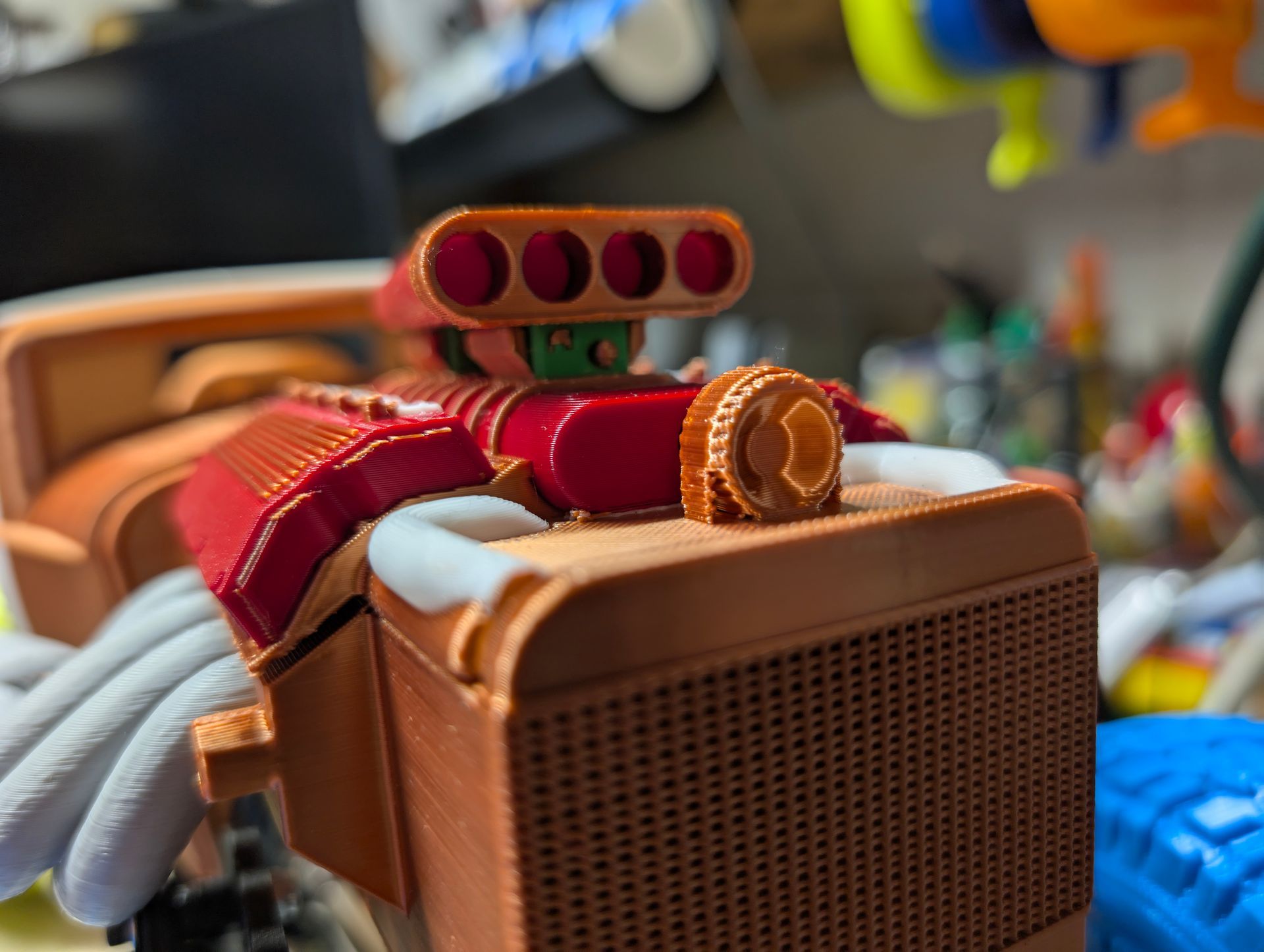 Close-up of a 3D-printed car engine model in reddish-brown, red, green, and orange.