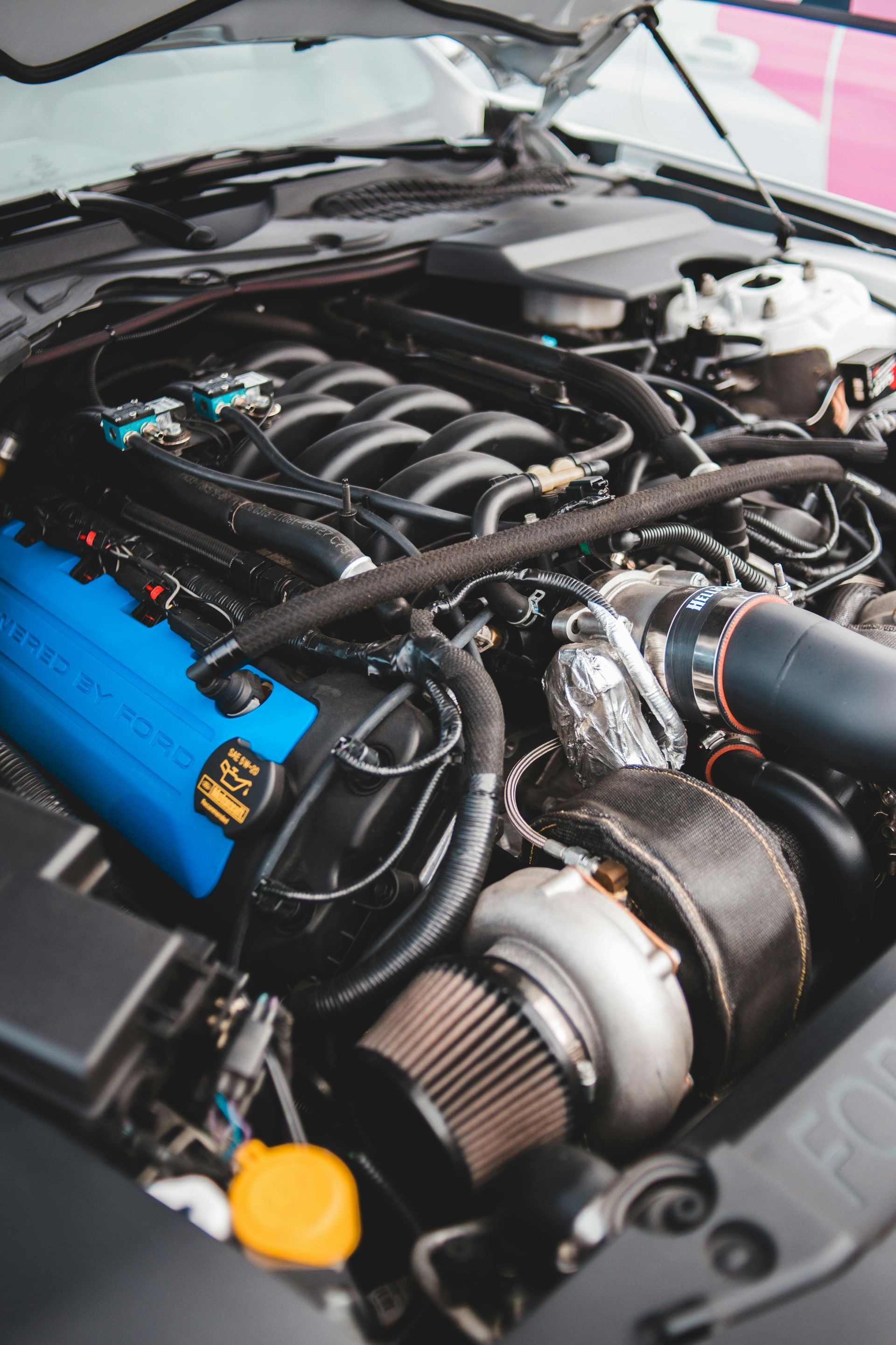 Close-up of a car engine bay with a blue valve cover and visible turbocharger components
