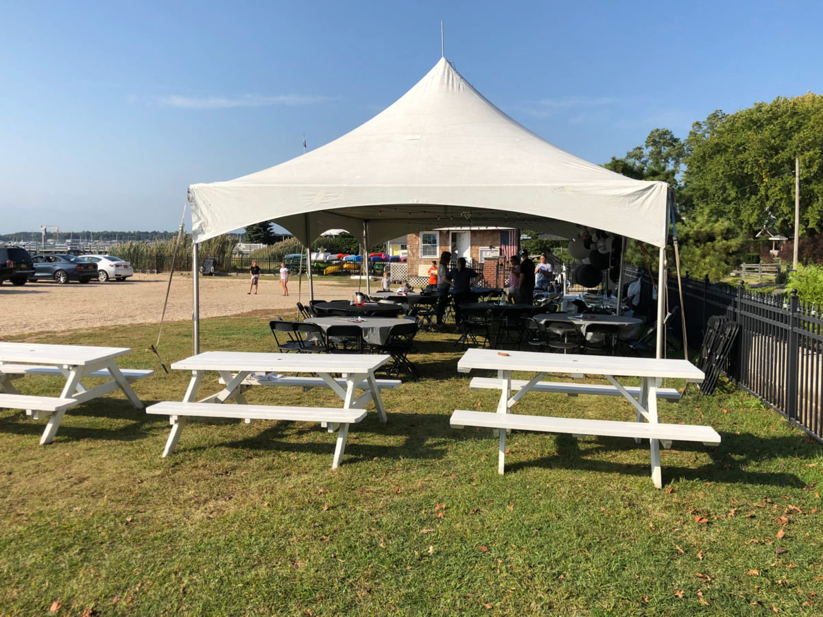 High-Peak Tent A group of white picnic tables under a white high-peak tent.