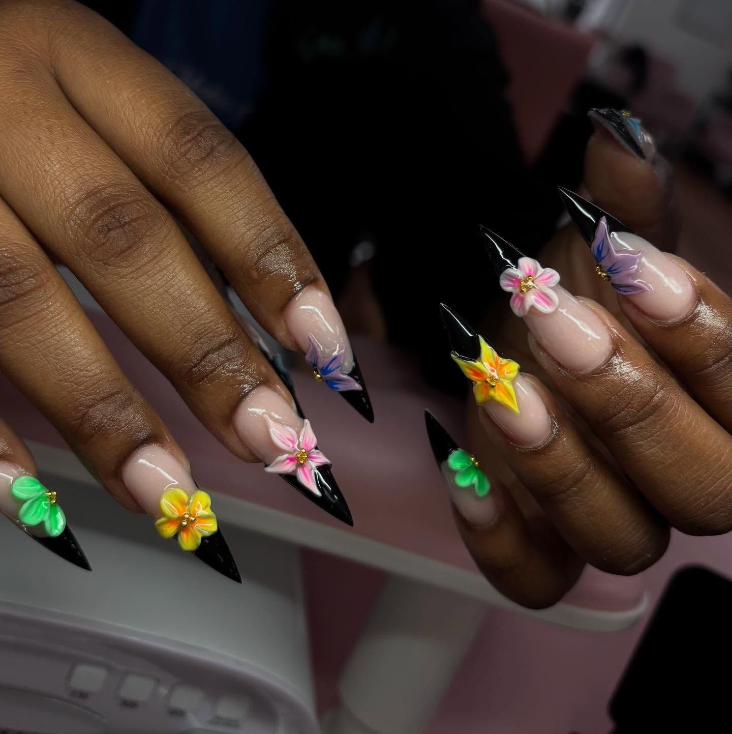 Long, black and white stiletto nails with 3D flower accents.