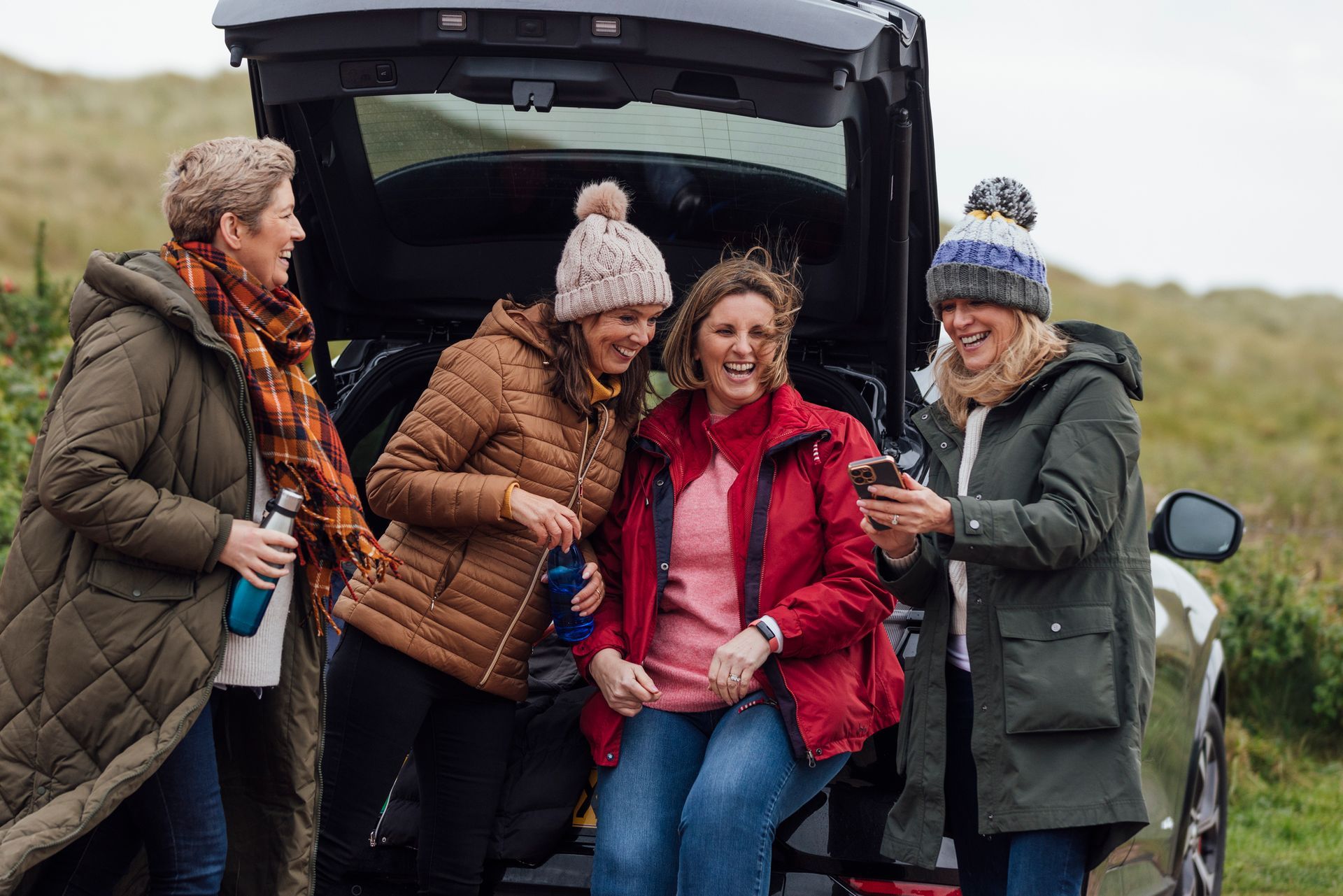 A Group of Women Are Sitting in The Back of A Car.