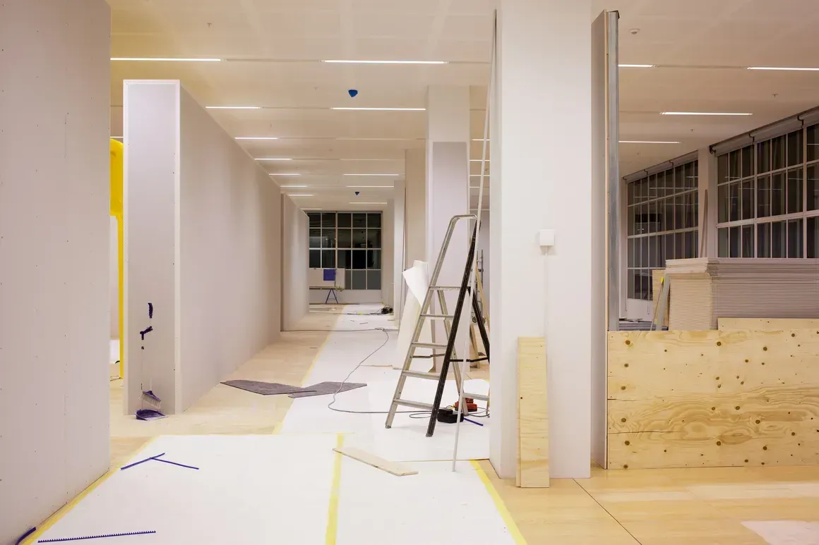 A hallway in a building under construction with a ladder on the floor.