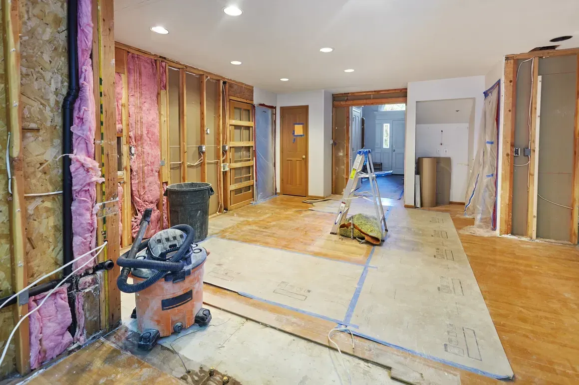 A room under construction with a vacuum cleaner on the floor.