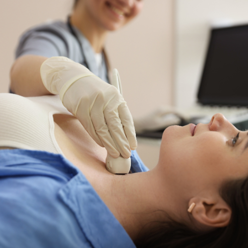 Woman receiving a neck ultrasound by a healthcare professional in a medical setting.