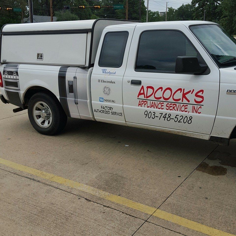 A white adcock 's appliance service truck is parked on the side of the road