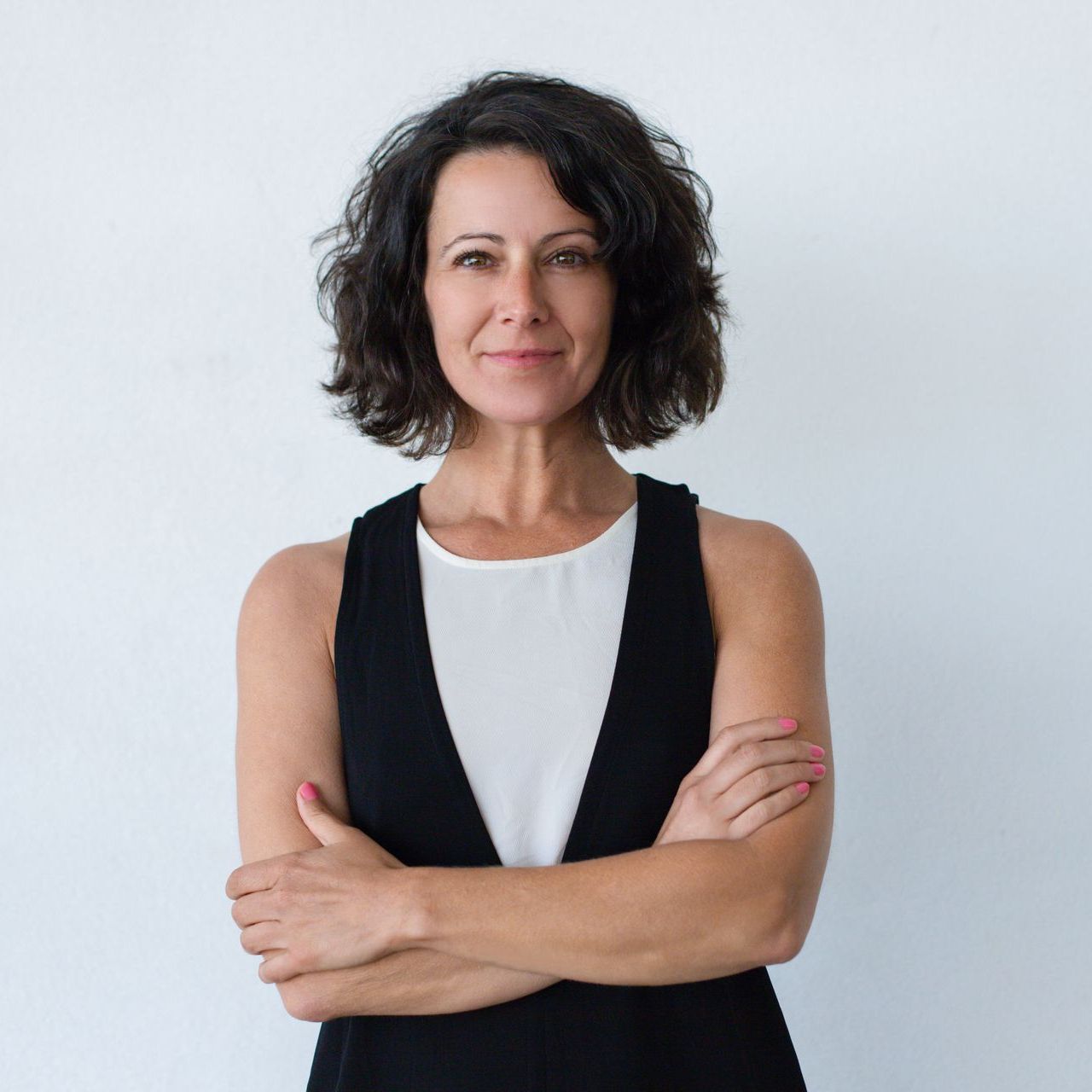 A woman is standing with her arms crossed and smiling.