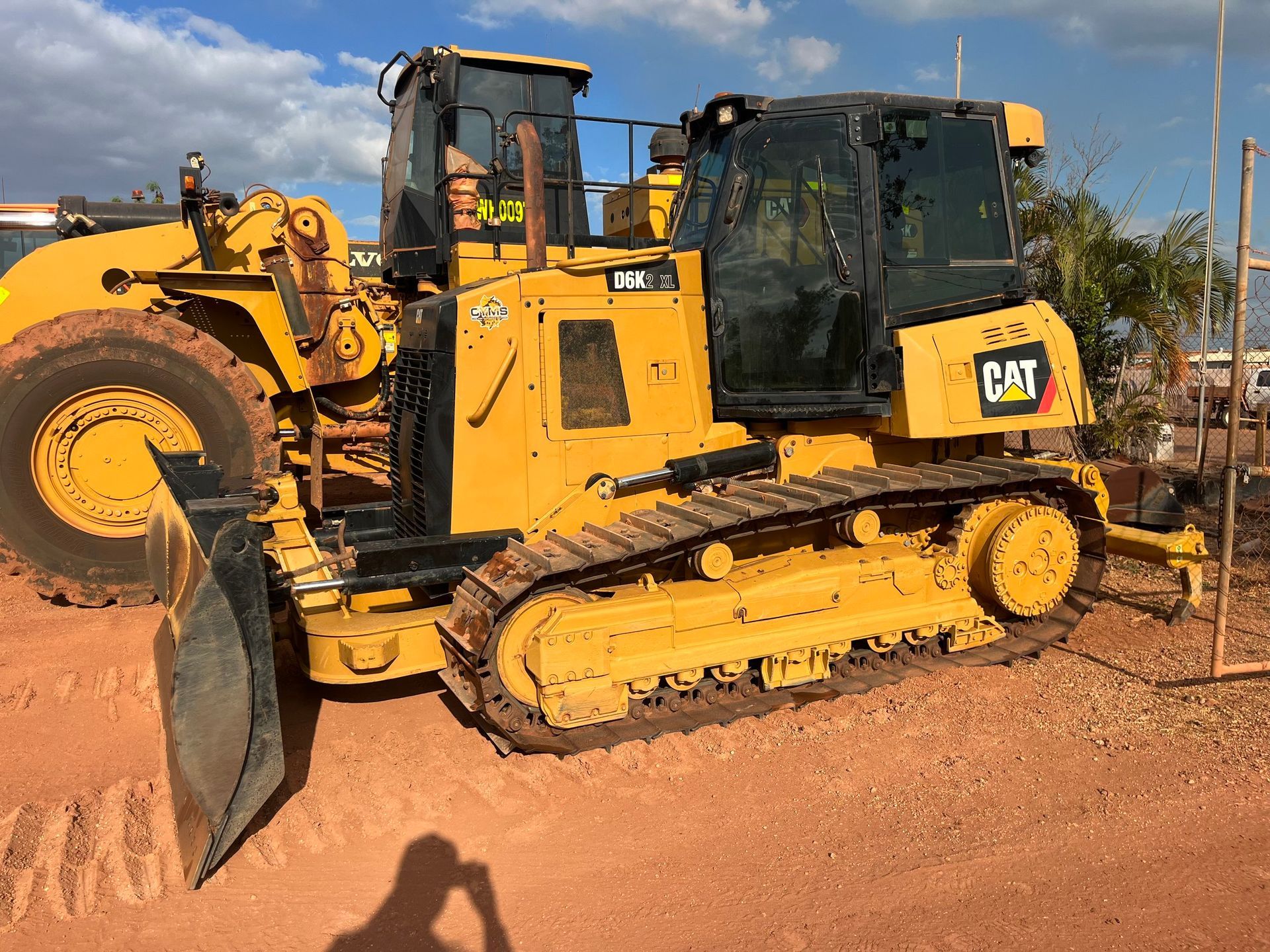 Yellow CAT bulldozer on a dirt site under a blue sky, with a front blade and tracks visible